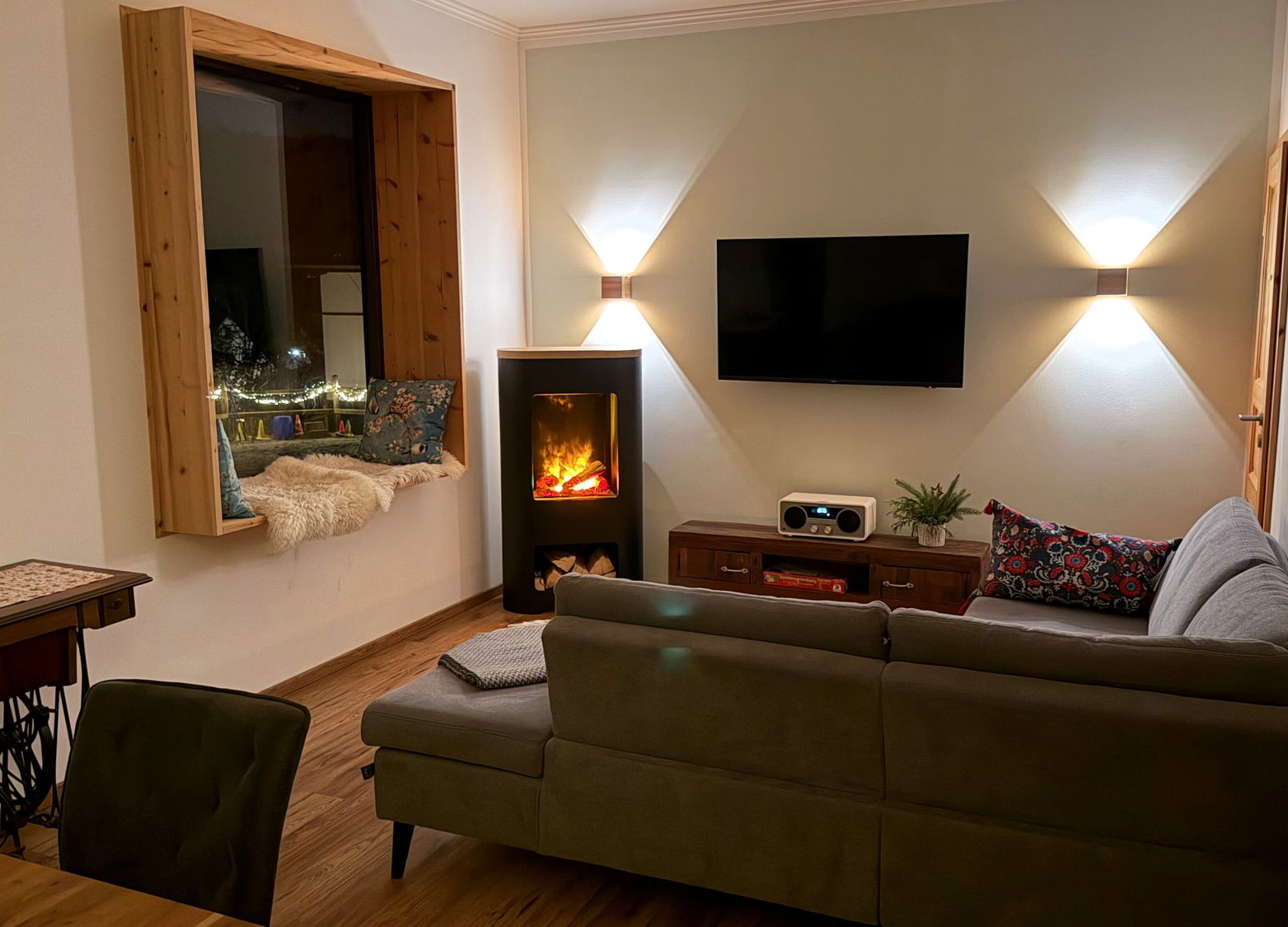 Das Wohnzimmer mit dem stimmungsvollen Flammenspiel des Elektrokamins im Ferienhaus Landchalet Eifel auf dem Landgut Pfauenhof in der Eifel.