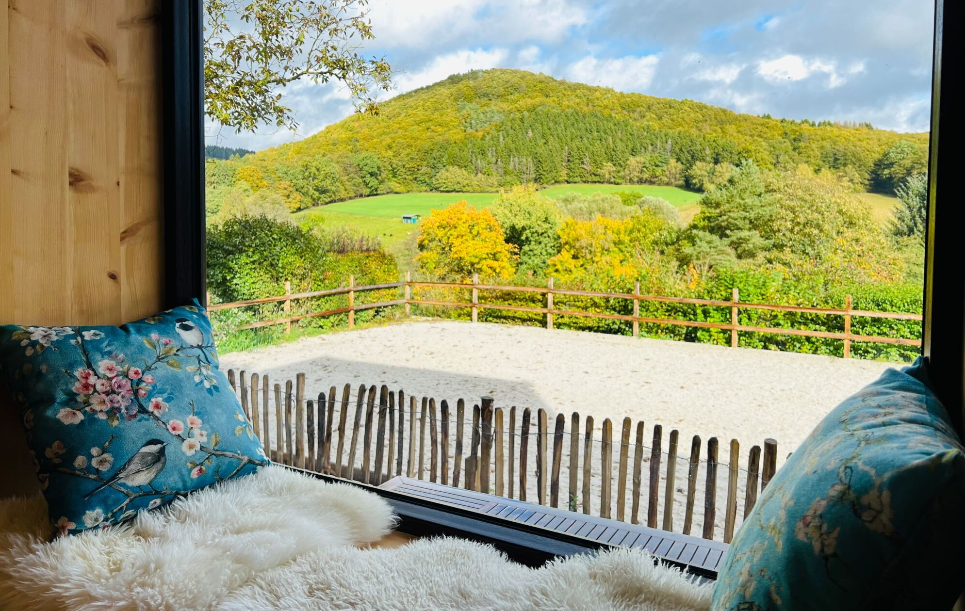 Ein Sitzfenster aus Zirbenholz im Landchalet Eifel auf dem Landgut Pfauenhof gibt den Blick auf eine wunderbare Landschaft frei.