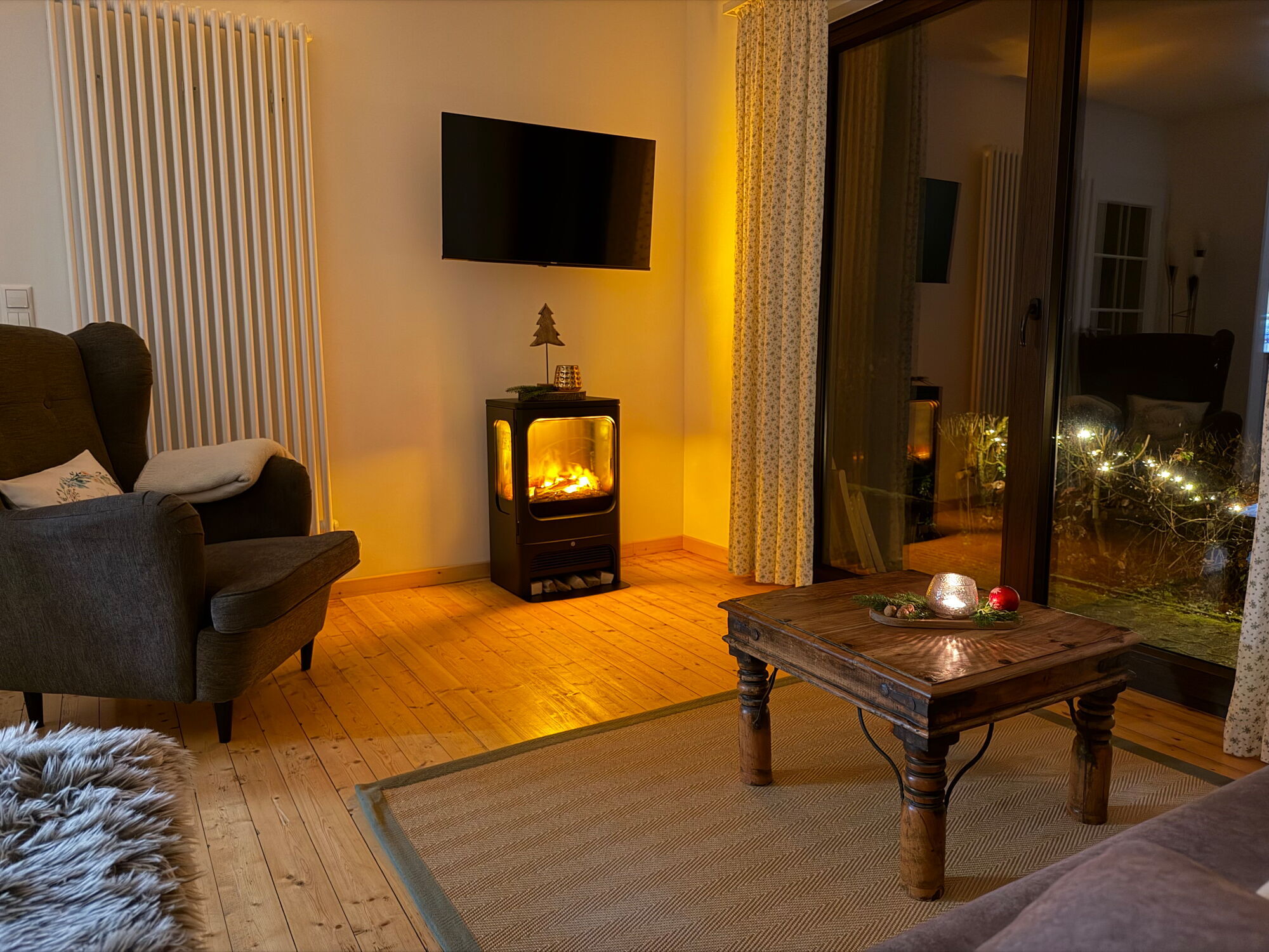 Blick von der Couch auf das stimmungsvolle Flammenspiel des Elektrokamins in der Ferienwohnung Eifelcottage auf dem Landgut Pfauenhof in der Eifel.