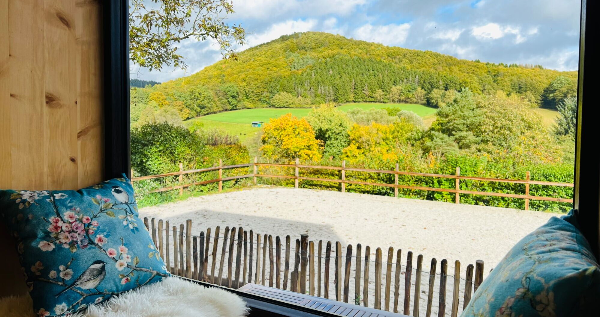 Ein Sitzfenster aus Zirbenholz im Landchalet Eifel auf dem Landgut Pfauenhof gibt den Blick auf eine wunderbare Landschaft frei.
